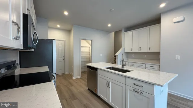 a kitchen with stainless steel appliances granite countertop a refrigerator a stove a sink dishwasher and a refrigerator with wooden floor