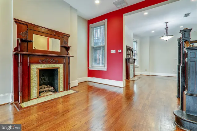 a view of an empty room with wooden floor and a fireplace