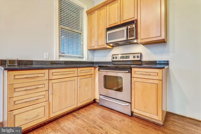 a kitchen with granite countertop cabinets stainless steel appliances and wooden floor