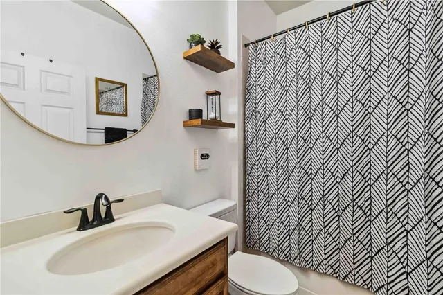 a bathroom with a sink a toilet and shower curtain