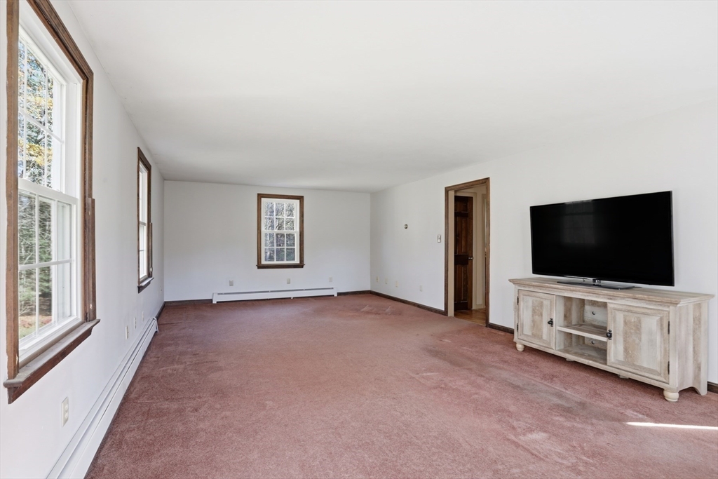 254 Ash Swamp Road Newmarket, NH 03857 - Photo 11 of 30 a view of a livingroom with entryway flat screen tv wooden shelves and windows