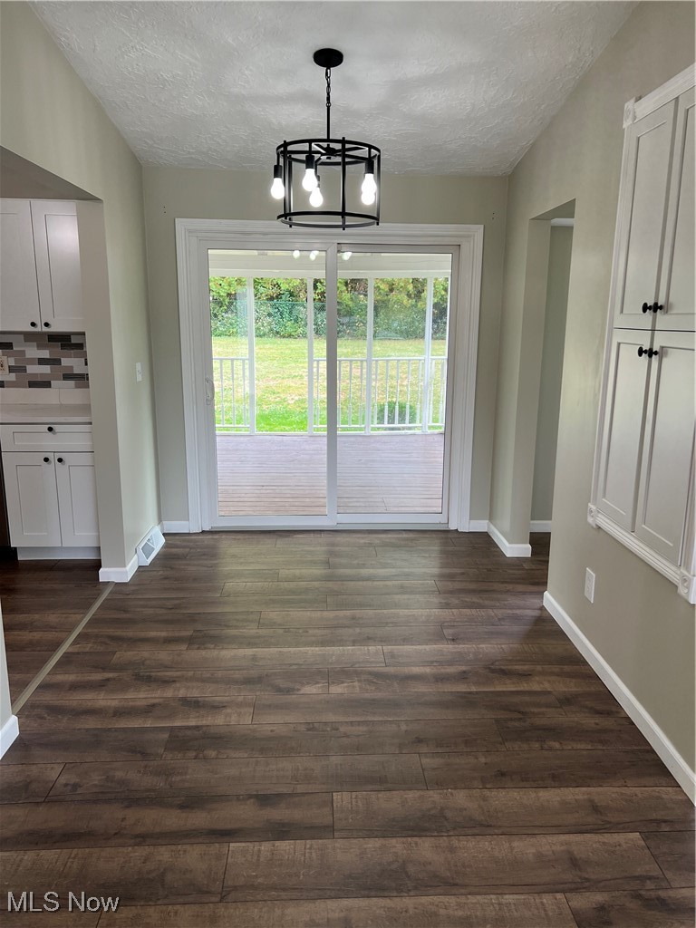 1715 Toepfer Road Akron, OH 44312 - Photo 7 of 49 Unfurnished dining area featuring an inviting chandelier, dark hardwood / wood-style floors, and a textured ceiling
