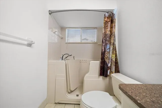 a white house with a yard plants and palm trees