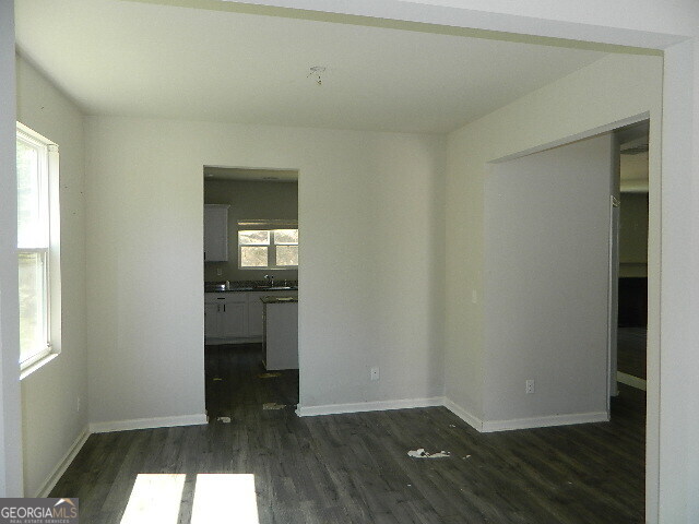 3790 River Rock Road Lithonia, GA 30038 - Photo 4 of 14 an empty room with wooden floor kitchen view and windows