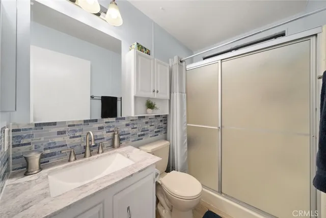 a bathroom with a granite countertop sink toilet mirror and shower