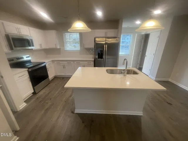 a kitchen with kitchen island a sink appliances and cabinets