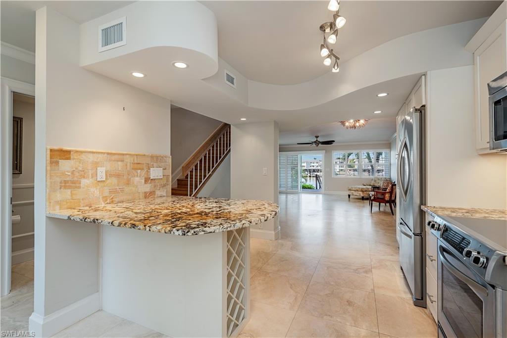 800 River Point Drive, Unit 207 Naples, FL 34102 - Photo 4 of 12 a view of open kitchen with kitchen island a stove a chimney a dining table and chairs