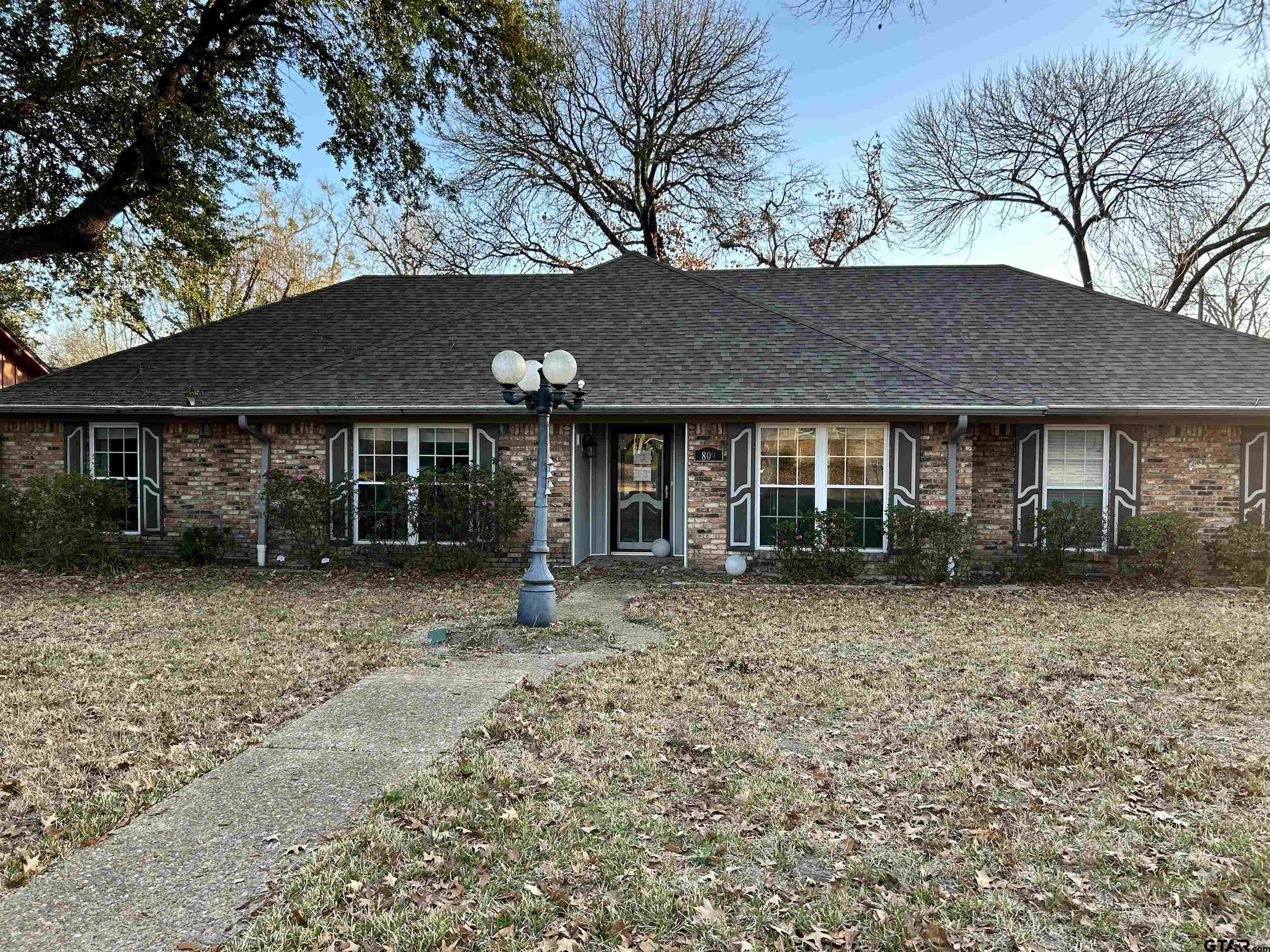 a front view of a house with a garden and trees