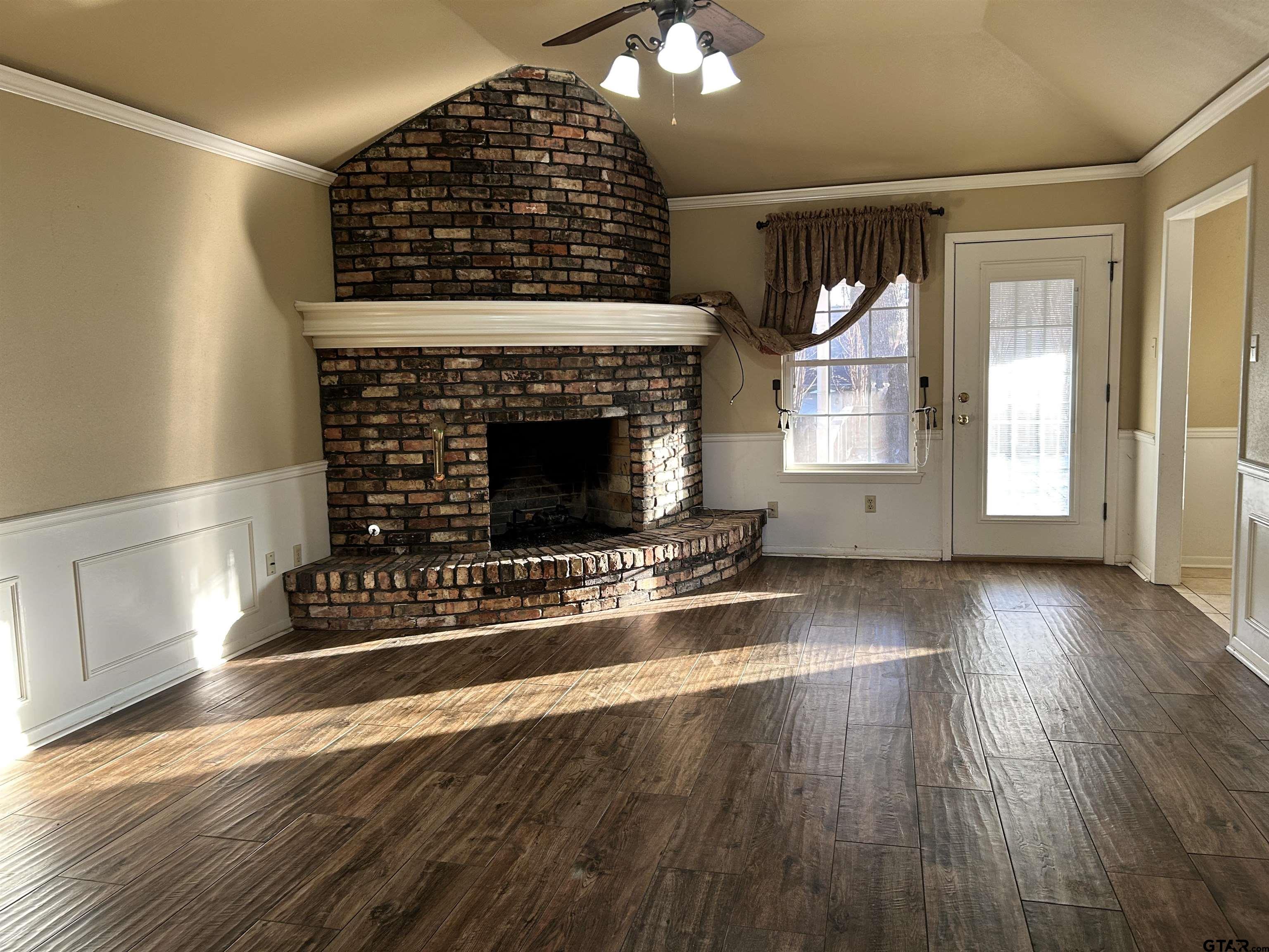 809 David Drive Tyler, TX 75703 - Photo 4 of 18 an empty room with wooden floor fireplace and windows