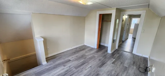 an empty room with wooden floor and a ceiling fan
