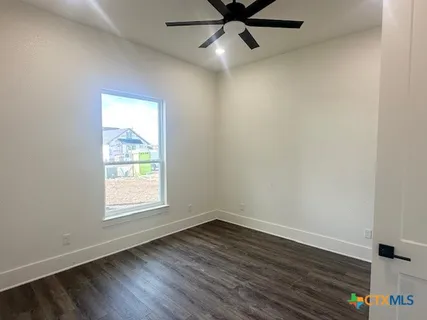 an empty room with wooden floor a ceiling fan and windows