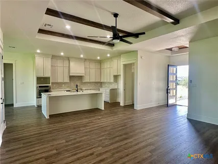 a view of a kitchen with kitchen island a island wooden floor stainless steel appliances and a ceiling fan
