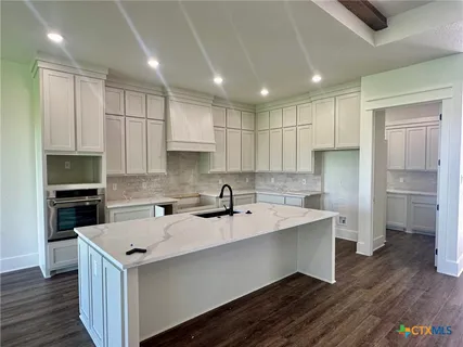 a kitchen with a sink a center island stainless steel appliances and cabinets