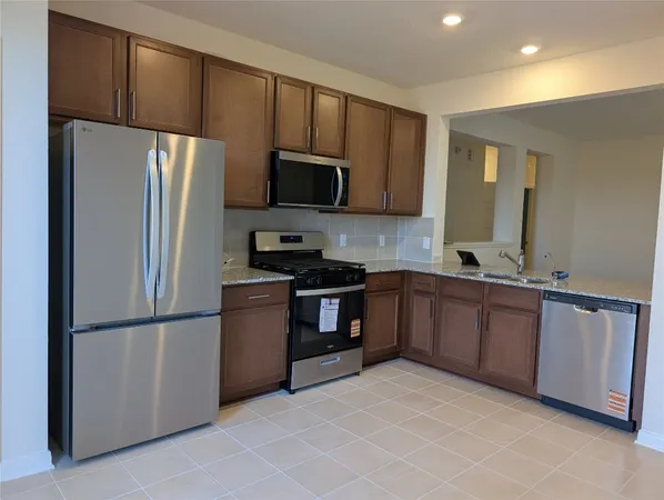 a kitchen with stainless steel appliances granite countertop a refrigerator a stove a sink and a microwave