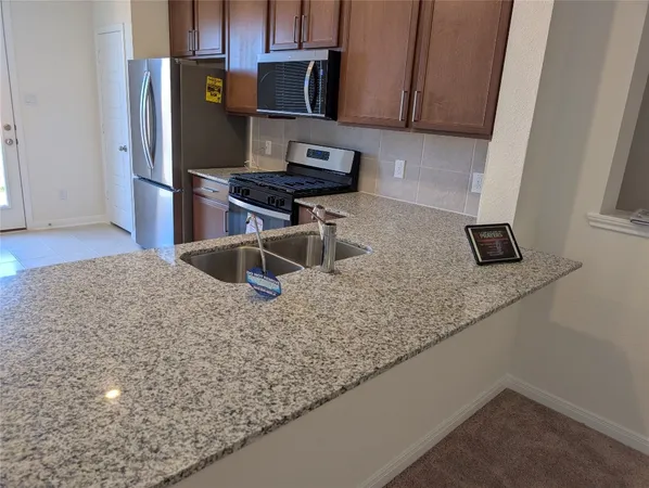 a kitchen with stainless steel appliances granite countertop a sink refrigerator and microwave