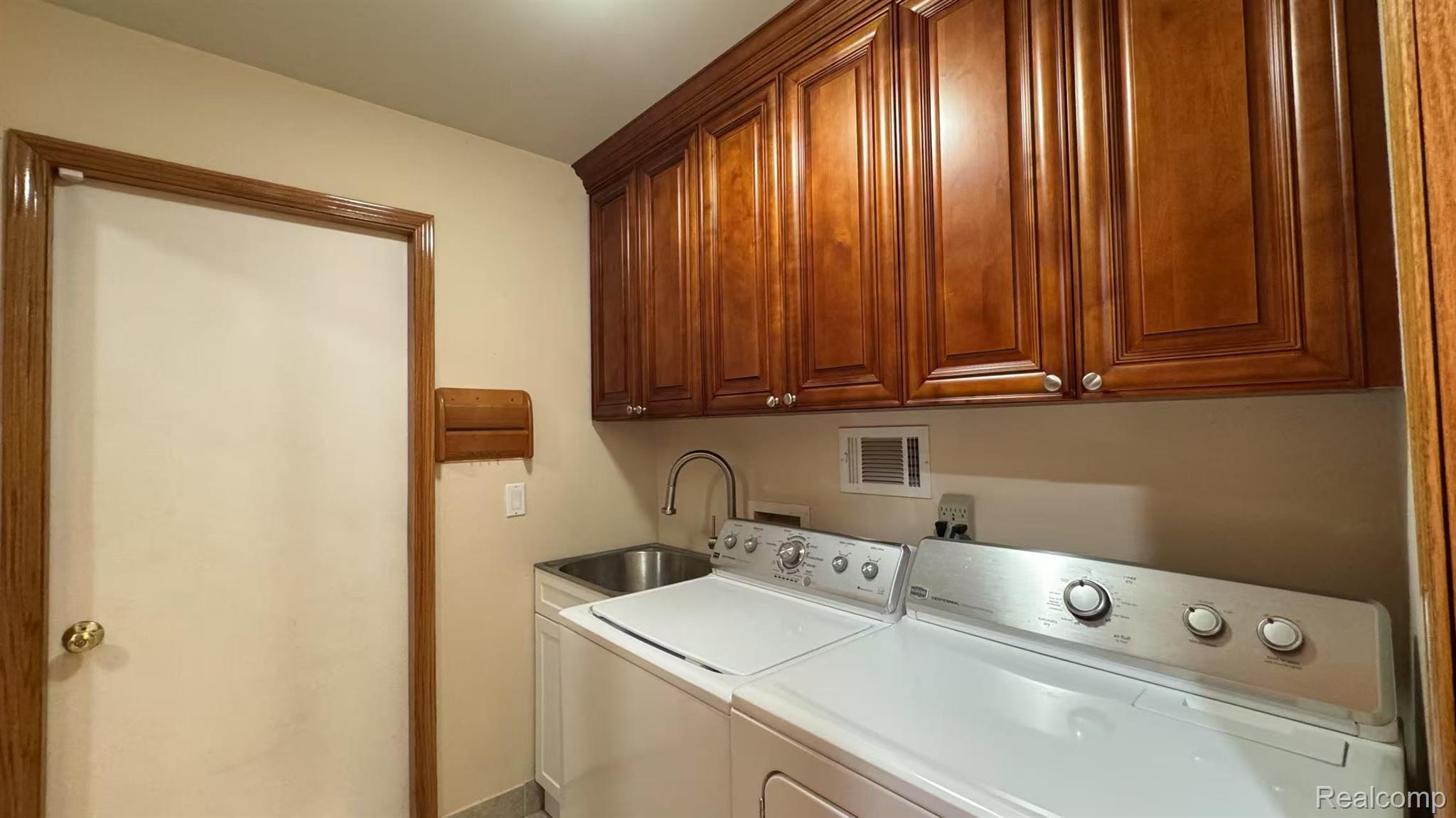 3440 Salem Drive Rochester, MI 48306 - Photo 18 of 33 Laundry room featuring extensive wood cabinetry, utility sink with a high-arc faucet, and tiled flooring
