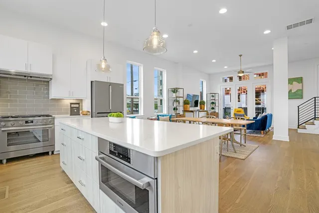 a large kitchen with kitchen island a stove a sink a center island and wooden floor