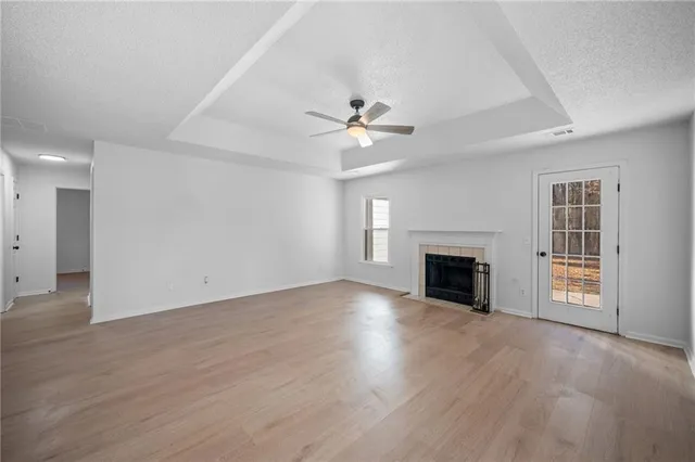 an empty room with windows fireplace and a ceiling fan