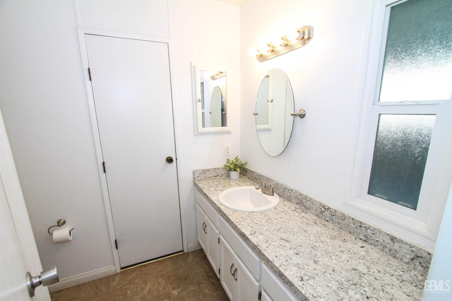 Undisclosed Address Bakersfield, CA 93301 - Photo 9 of 27 a bathroom with a granite countertop sink and a mirror