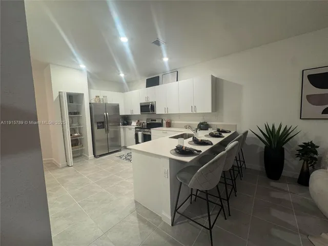 a kitchen with stainless steel appliances a table chairs refrigerator and cabinets