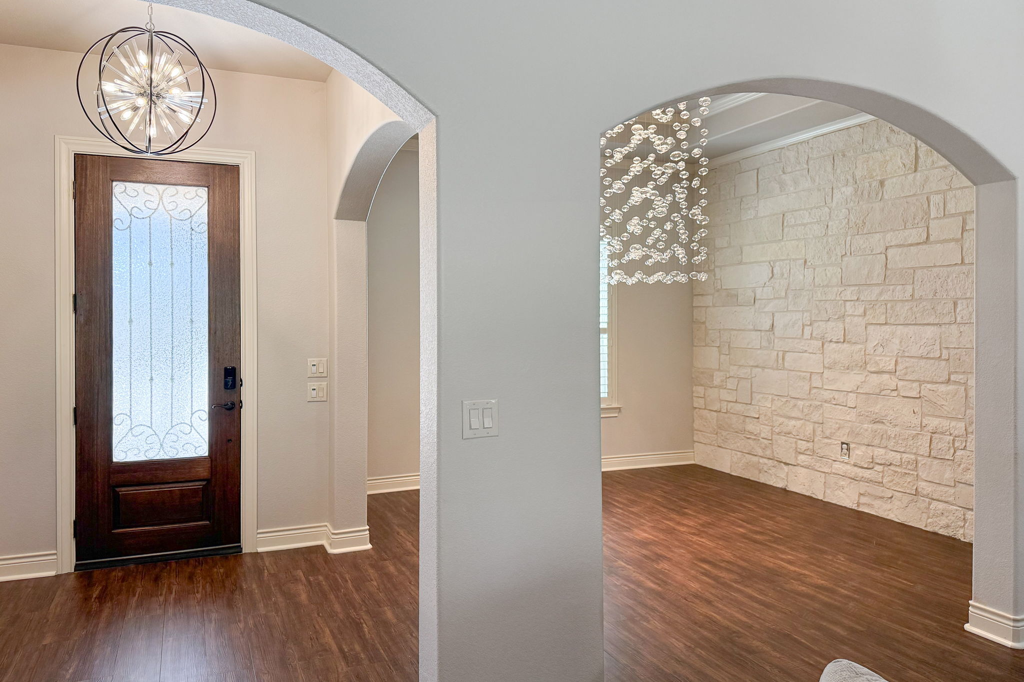 231 Marbella Way Georgetown, TX 78633 - Photo 13 of 40 Elegant arched entryways open to a welcoming space with wood flooring and a distinctive stone accent wall.