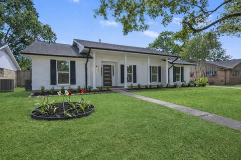 a front view of a house with a garden and trees