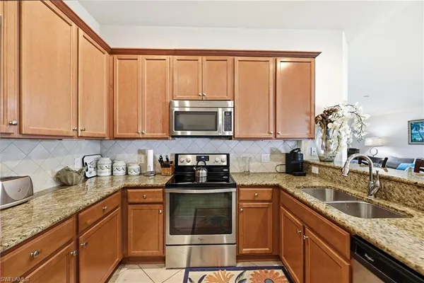 a kitchen with granite countertop a sink stove and microwave