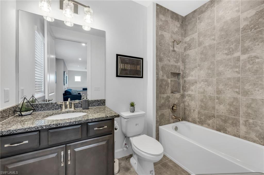 3410 Wellfleet Lane Naples, FL 34114 - Photo 16 of 28 a bathroom with a granite countertop sink a toilet a mirror a bathtub and shower