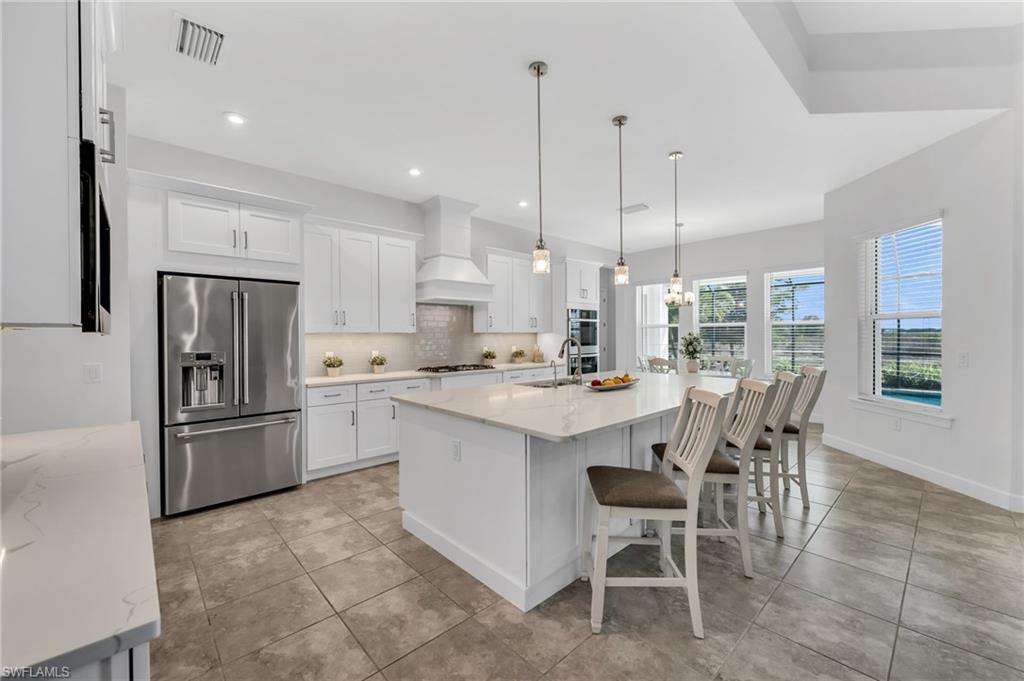 3410 Wellfleet Lane Naples, FL 34114 - Photo 10 of 28 a kitchen with kitchen island a dining table chairs appliances and a counter top space