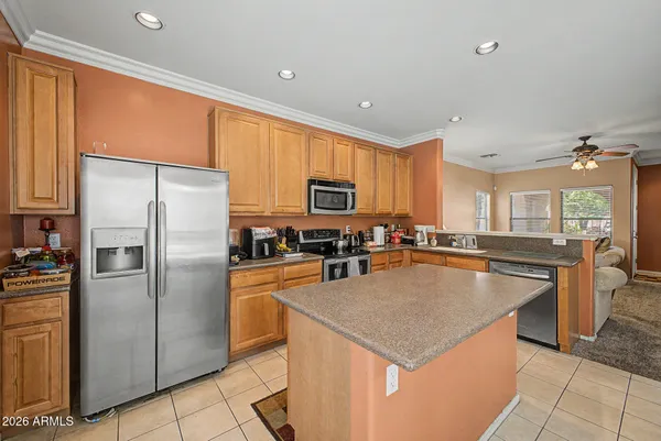 a kitchen with stainless steel appliances granite countertop a refrigerator a stove a sink a dining table and chairs