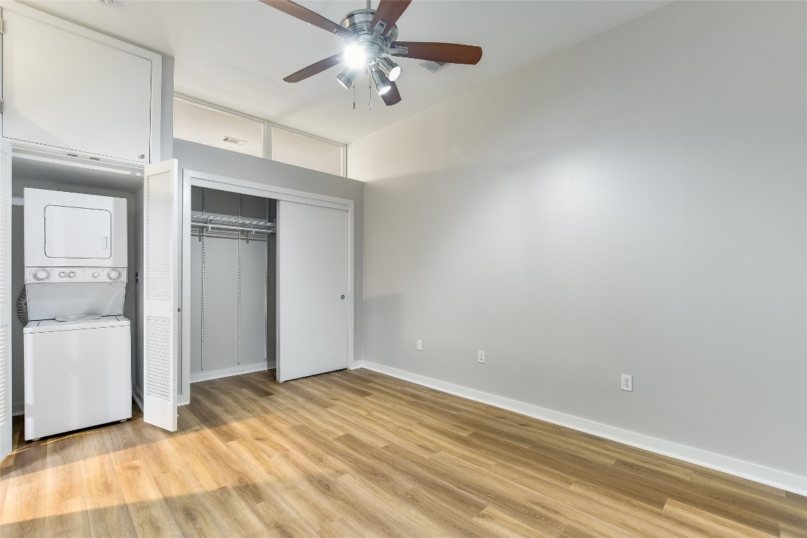 507 Sabine Street, Unit 709 Austin, TX 78701 - Photo 11 of 13 Unfurnished bedroom featuring stacked washer / dryer, a closet, light wood finished floors, and ceiling fan