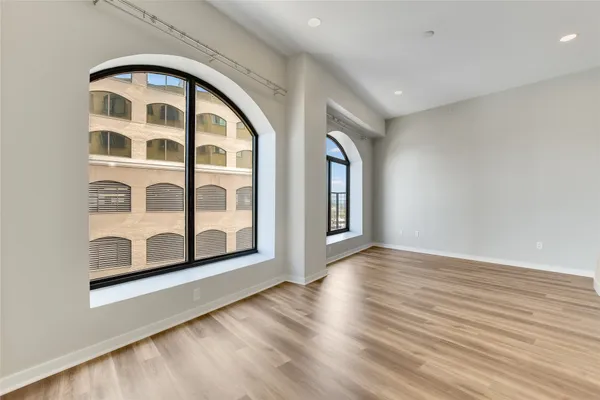 a view of an empty room with wooden floor and windows