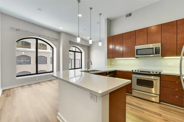 a kitchen with stainless steel appliances granite countertop a sink a stove and a wooden floors