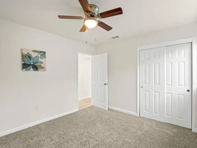 an empty room with closet and a ceiling fan