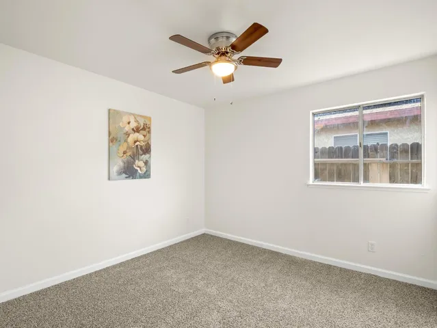 an empty room with window and ceiling fan