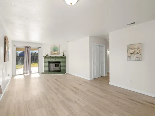 an empty room with wooden floor fireplace and windows