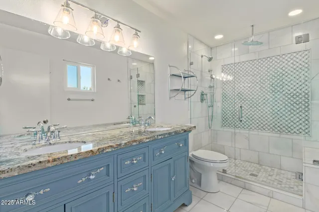 a bathroom with a granite countertop double vanity sink a mirror and a shower