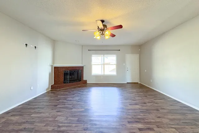 a view of an empty room with window and wooden floor