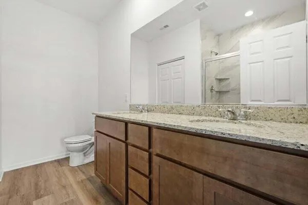 a bathroom with a granite countertop sink a toilet and a mirror
