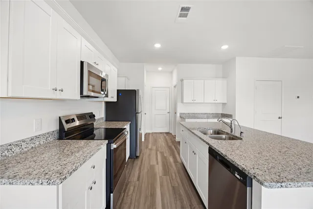 a large kitchen with stainless steel appliances granite countertop a stove a sink and white cabinets