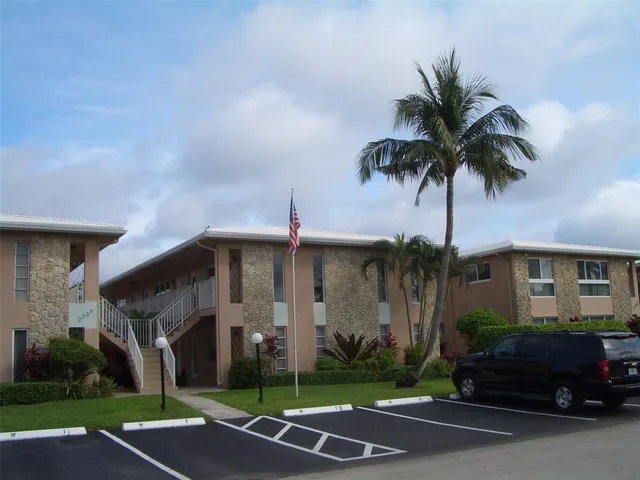 a palm tree sitting in front of a house with a yard