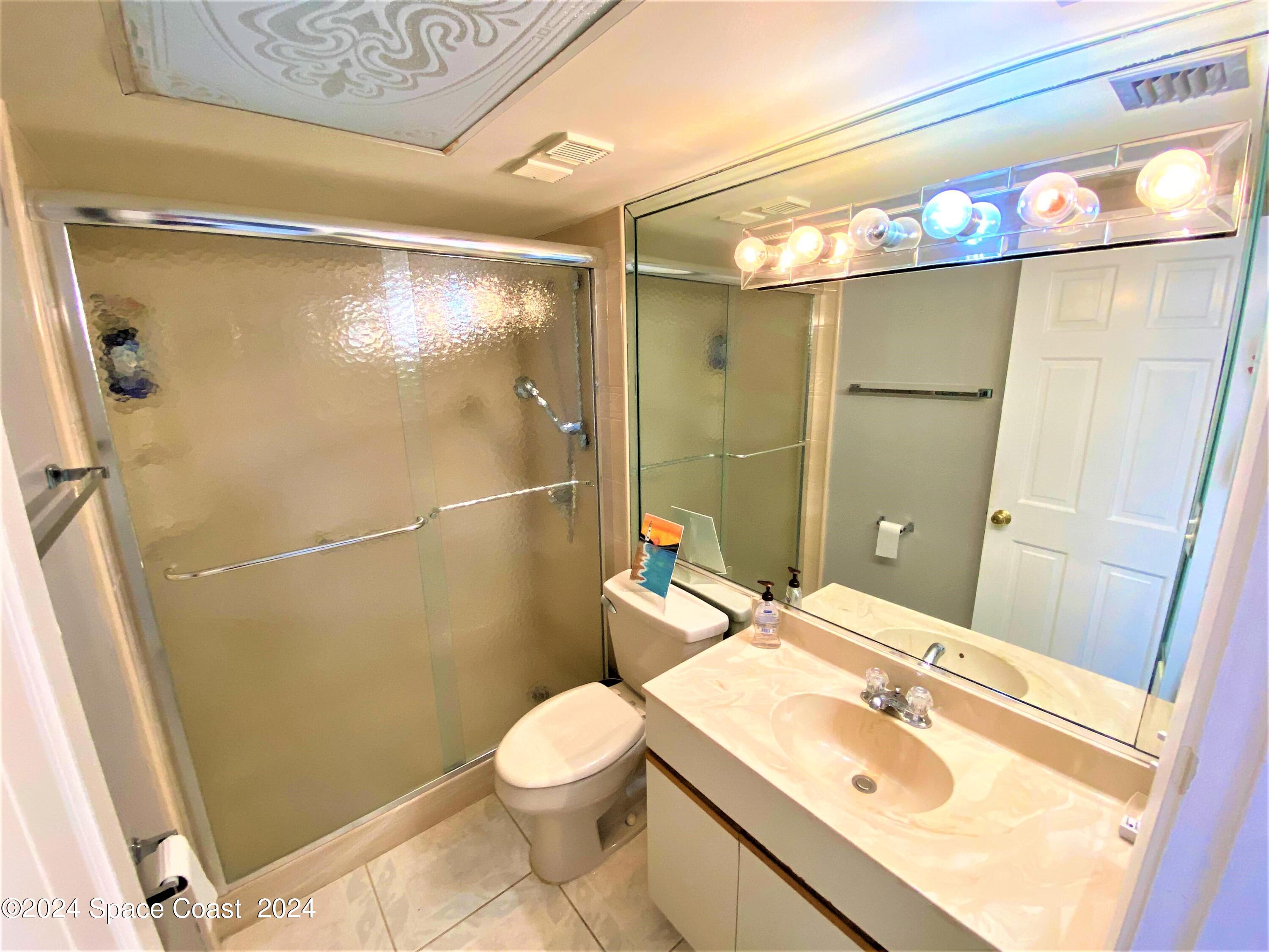 2100 North Atlantic Avenue, Unit 908 Cocoa Beach, FL 32931 - Photo 13 of 17 a bathroom with a sink mirror vanity and toilet