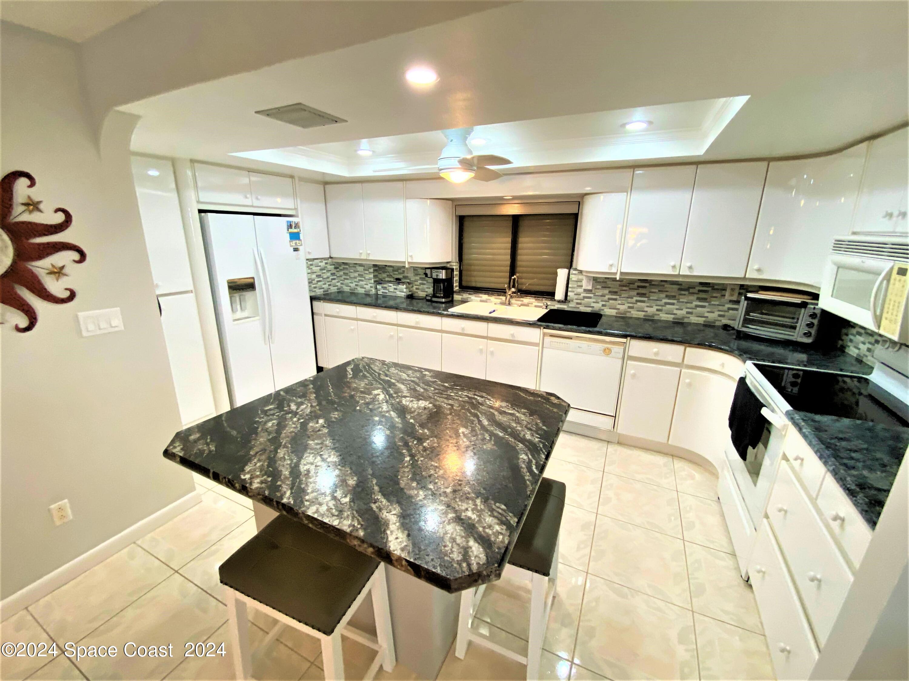 2100 North Atlantic Avenue, Unit 908 Cocoa Beach, FL 32931 - Photo 5 of 17 a kitchen with stainless steel appliances granite countertop a sink and cabinets
