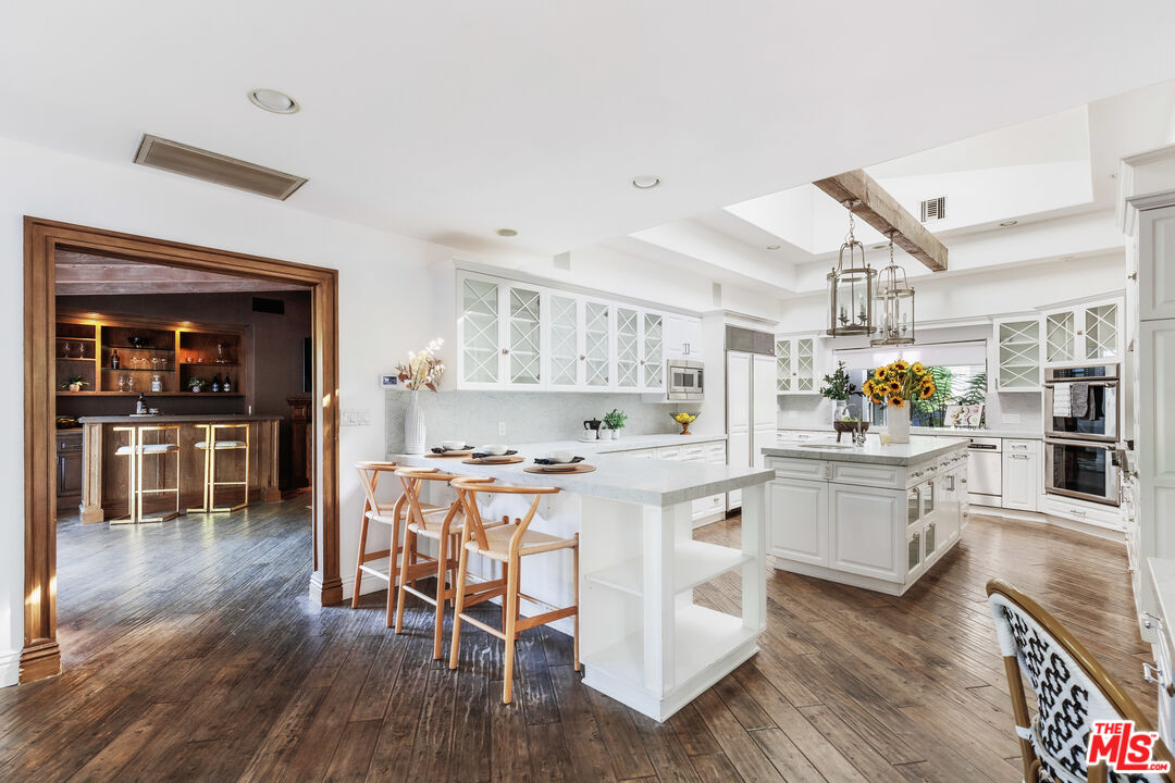 15475 Milldale Drive Los Angeles, CA 90077 - Photo 8 of 22 a kitchen with a dining table chairs stove and cabinets