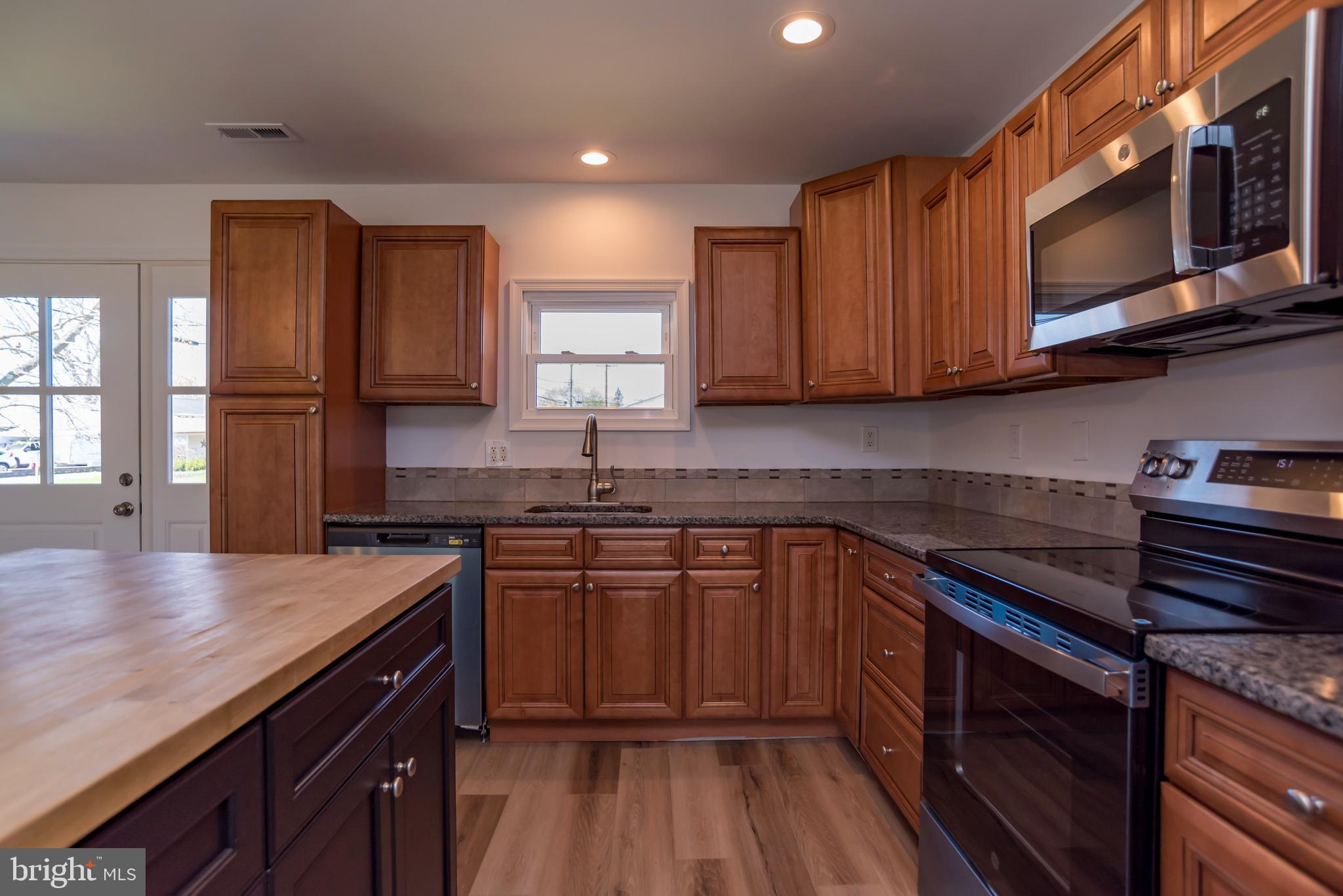 44 Elm Lane Levittown, PA 19054 - Photo 7 of 35 a kitchen with stainless steel appliances granite countertop wooden cabinets a stove top oven a sink and dishwasher with wooden floor