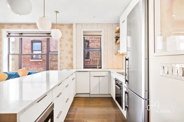 a kitchen with granite countertop a table chairs stove a sink dishwasher and white cabinets with wooden floor