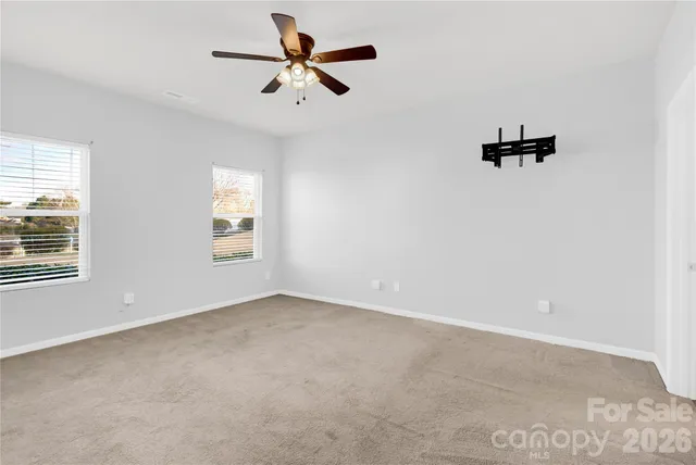an empty room with windows and ceiling fan