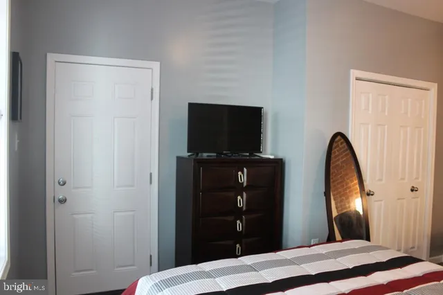 a bedroom with a bed and a flat tv screen on dresser