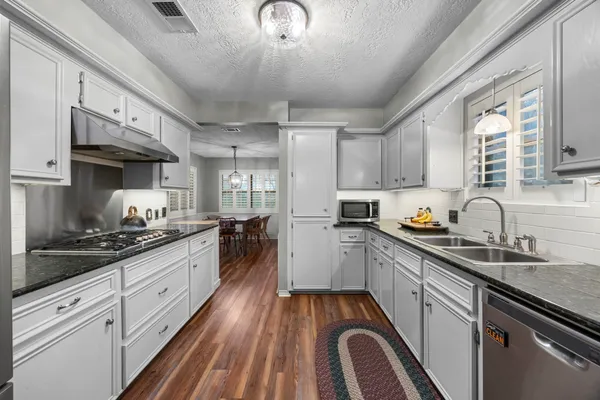 a kitchen with a stove and wooden floor
