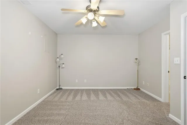an empty room with chandelier fan and closet area